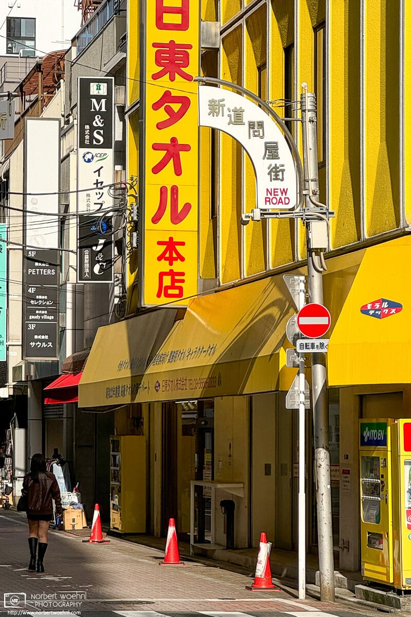 The strikingly yellow Nitto Towel Building in the Bakurocho area of Tokyo. An interesting area for street photography, it is worth to wait a few minutes and see what happens and who (or what) shows up as a potential photo subject. © 2024 Norbert Woehnl Photography.