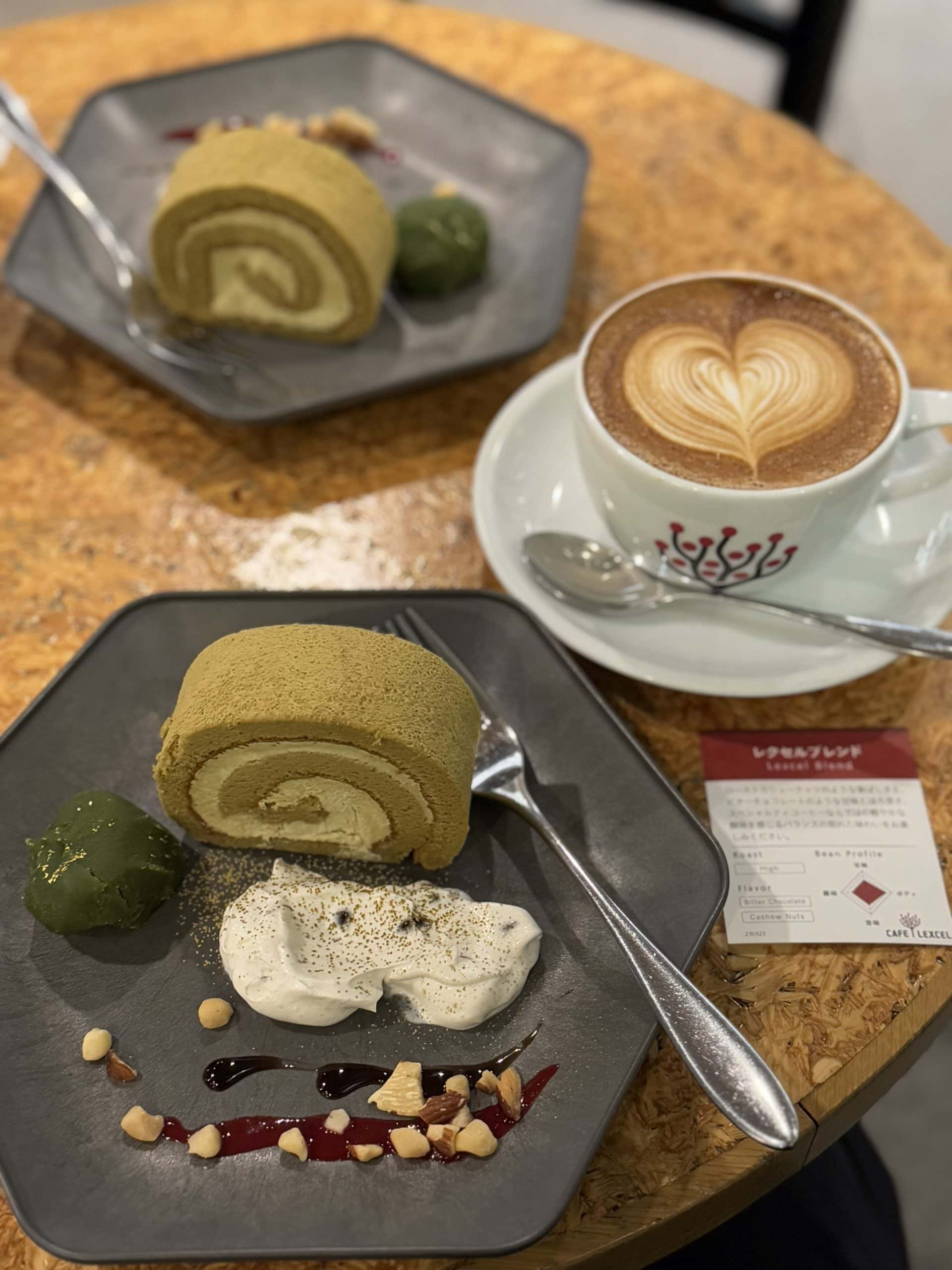 Photo of a cup of Caffe Latte and a Hojicha (roasted green tea) roll cake with various garnishes, taken at a cafe in Tokyo. © 2025 Norbert Woehnl Photography.